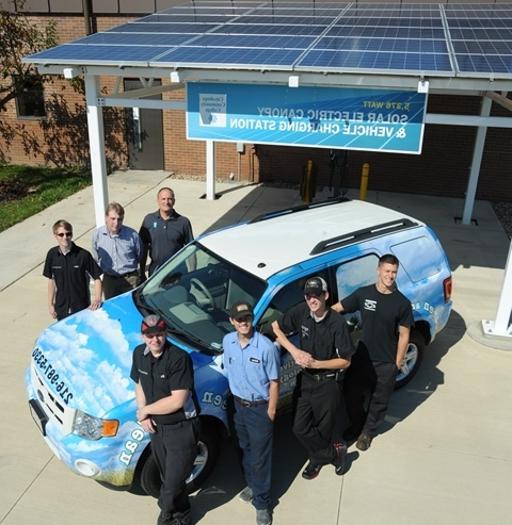 Automotive Technology students in front of the program's solar panels and electric vehicle charging station